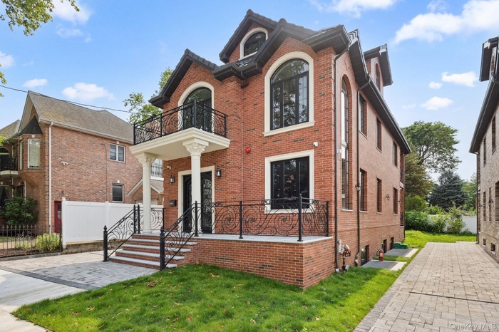 View of front of house with a balcony and brick siding