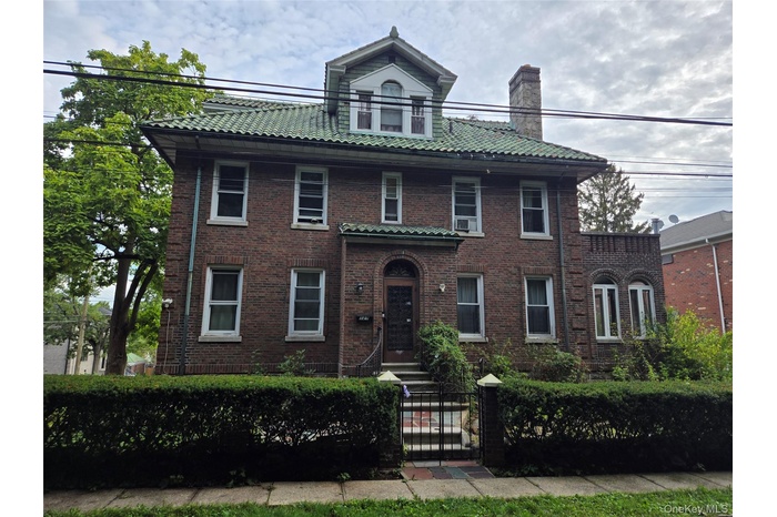 View of front of home featuring brick siding, a gate, a fenced front yard, and a chimney