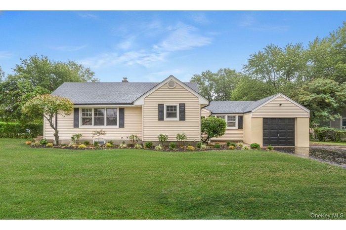 View of front of house with a front lawn, a chimney, a garage, driveway, and a shingled roof - edited