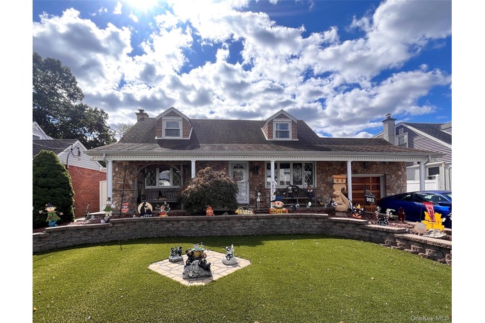 View of front of house with stone siding, a front lawn, a porch, and a shingled roof