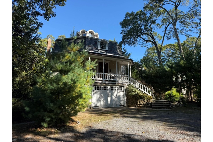Victorian home featuring mansard roof, a porch, stairs, driveway, and an attached garage