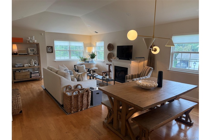 Dining space featuring a fireplace, light wood finished floors, healthy amount of natural light, and vaulted ceiling