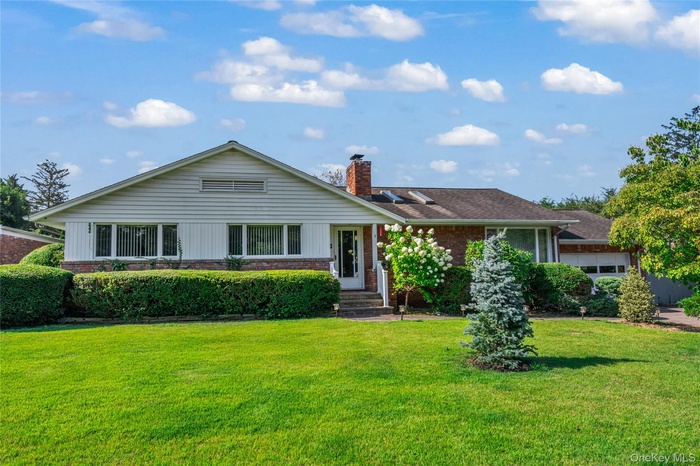 Ranch-style house featuring brick siding, a front yard, and a chimney