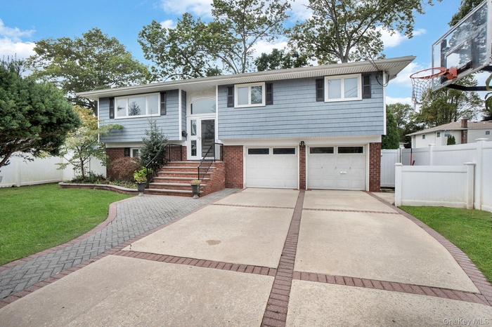Raised ranch with brick siding, driveway, and an attached garage