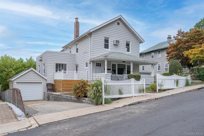 Traditional style home featuring a fenced front yard,, a porch, a garage, and a chimney