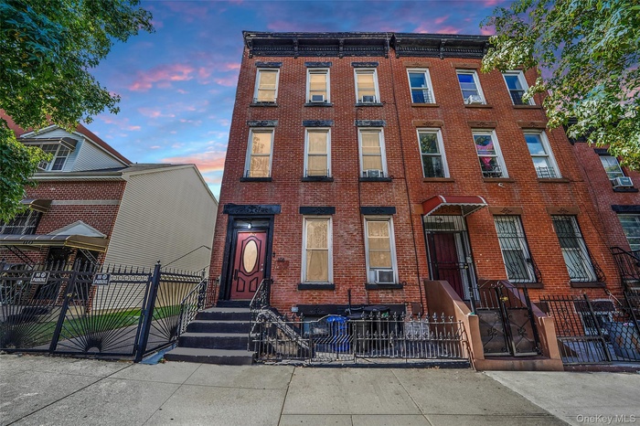 Italianate house featuring a fenced front yard, a gate, and brick siding
