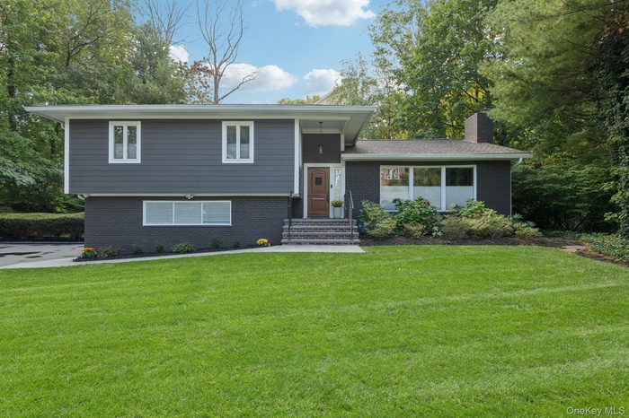 Tri-level home with brick siding, a front lawn, and a chimney