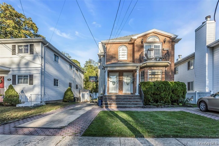 Traditional home with brick siding, a balcony, and a front lawn