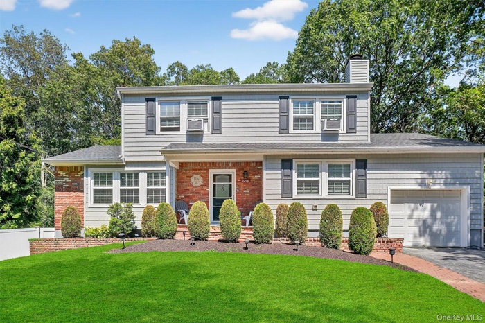 Traditional-style home with a chimney, a garage, driveway, and brick siding