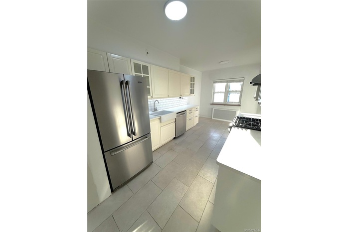 Kitchen featuring appliances with stainless steel finishes, glass insert cabinets, tasteful backsplash, and white cabinets