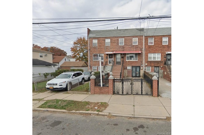 View of front facade with a fenced front yard, brick siding, and a gate