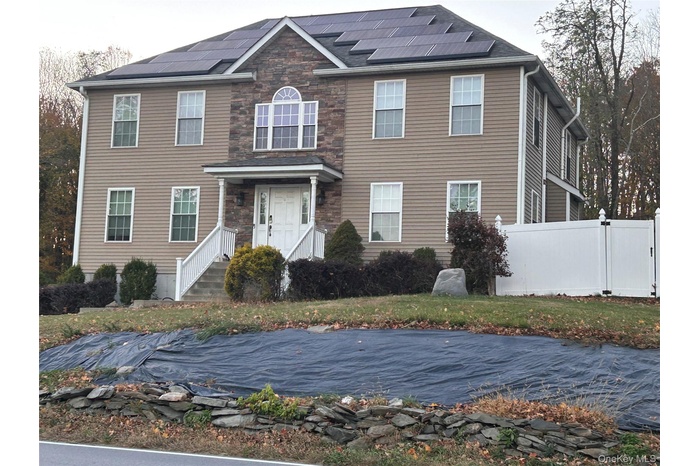View of front of home featuring roof mounted solar panels and stone siding