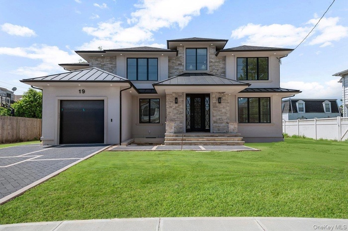 View of front of property with a standing seam roof, an attached garage, driveway, and metal roof
