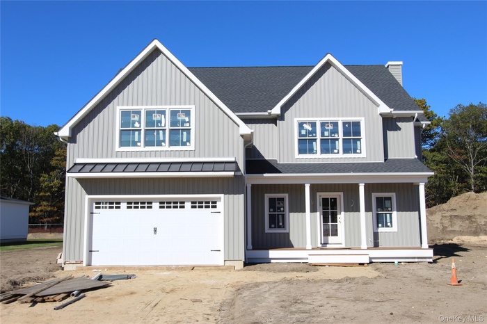 Modern farmhouse with roof with shingles, covered porch, a garage, a chimney, and driveway