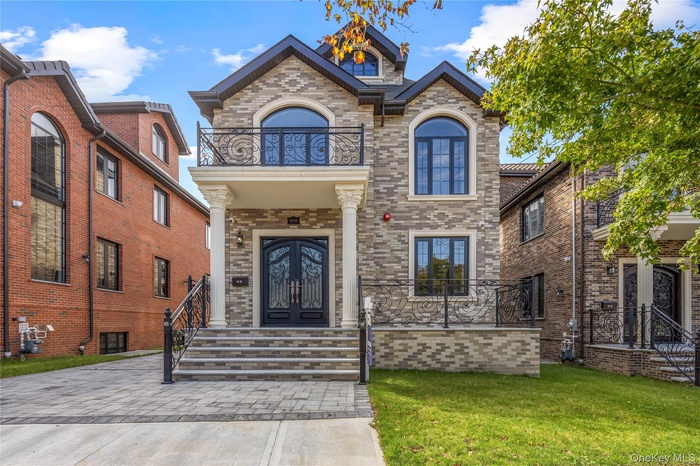 View of front of property featuring brick siding, french doors, a front lawn, and a balcony