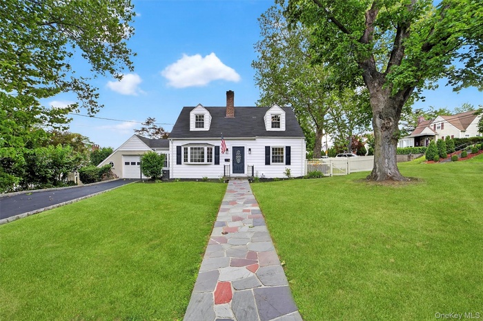 Cape cod-style house featuring driveway and a chimney