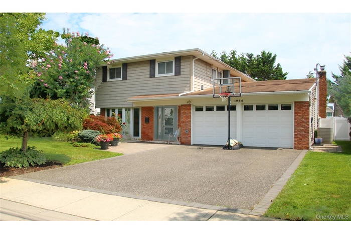 Traditional-style home featuring a front lawn, driveway, brick siding, and an attached garage