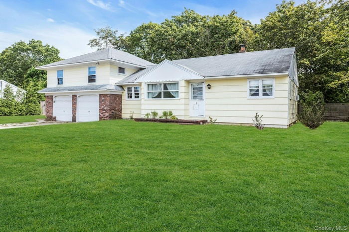 View of front of home with a front lawn, driveway, and an attached garage