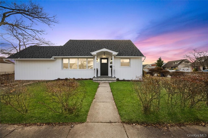 View of front of house with a shingled roof and a yard