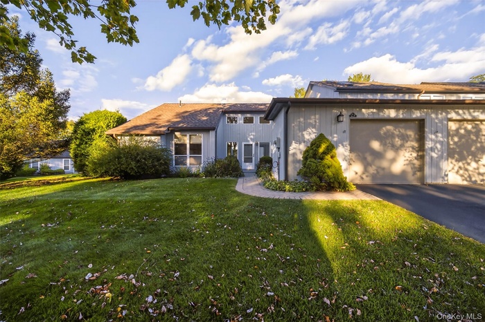 View of front of house with driveway, a garage, and a front lawn