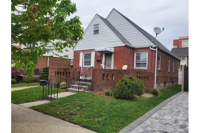 View of front of property featuring brick siding, a front lawn, and a shingled roof