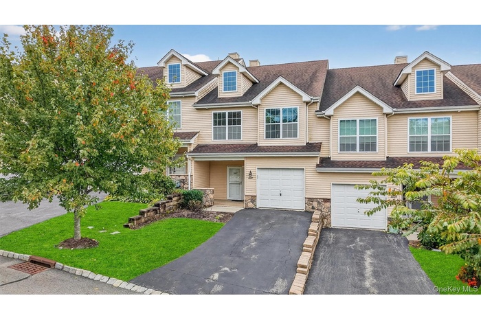 View of front of home featuring a chimney, driveway, stone siding, and a shingled roof