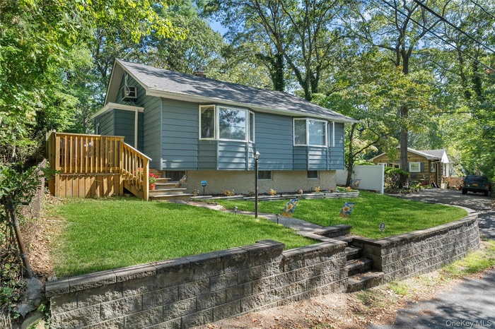 View of front facade with a front lawn, view of wooded area, stairway, and a chimney
