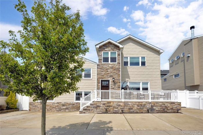 View of front of property with stone siding and fence