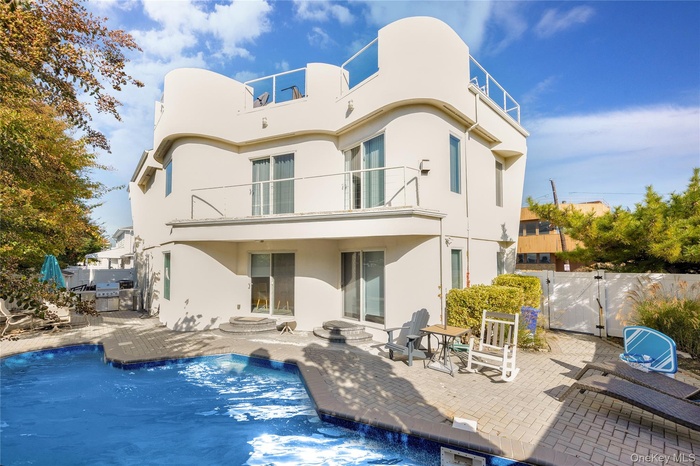 Back of property featuring a patio, a balcony, fence, a gate, and stucco siding