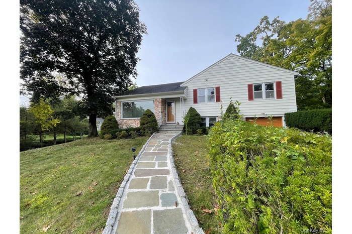 Split level home with a front yard and stone siding