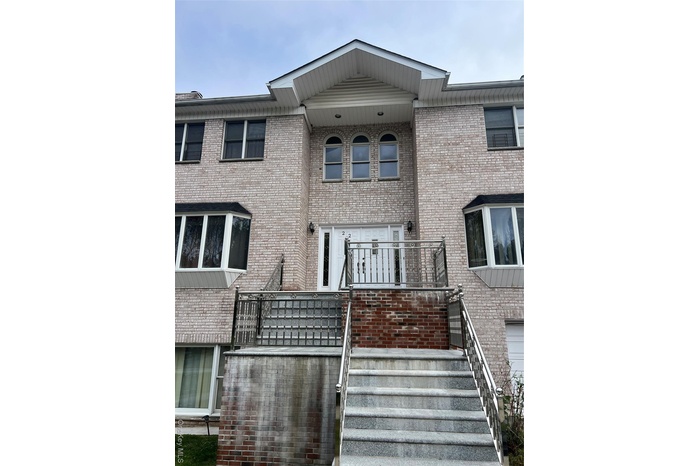 View of front of property with brick siding, stairs, and a balcony