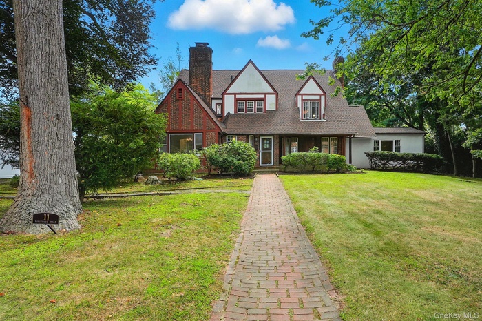 Tudor house with a chimney, a front lawn, and a shingled roof