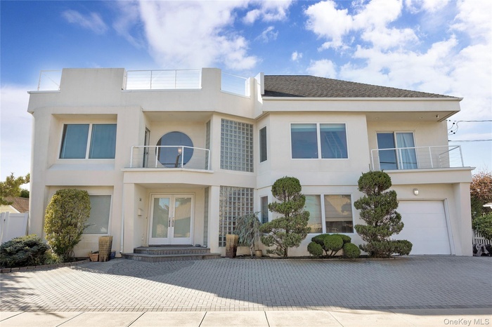 View of front of property with french doors, a balcony, and stucco siding