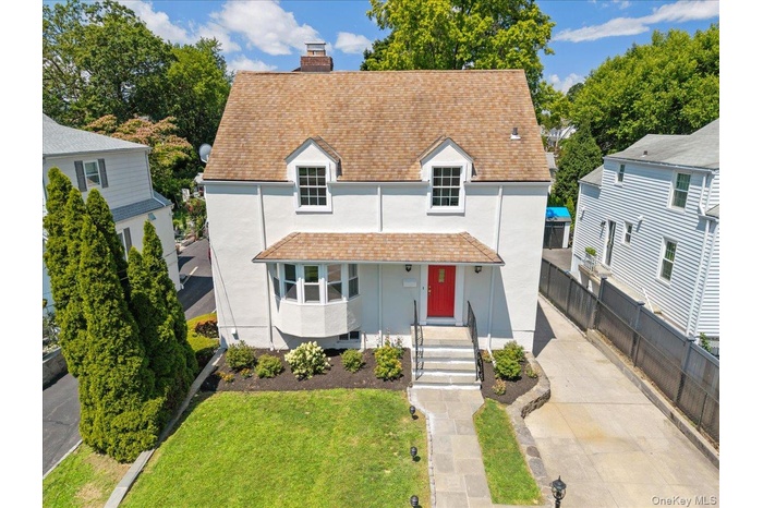View of front of house with roof with shingles, a chimney, and stucco siding
