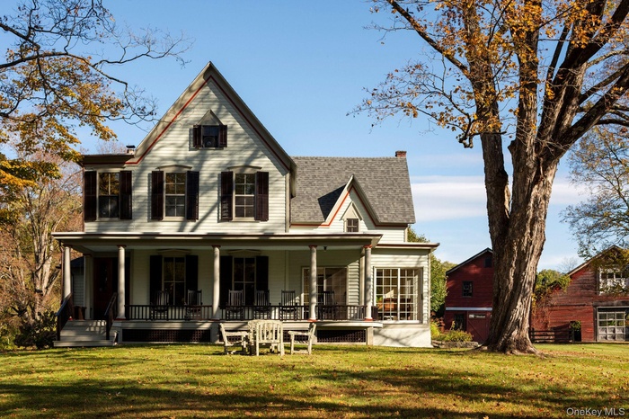View of front of property featuring covered porch, a front yard, a shingled roof, and a chimney