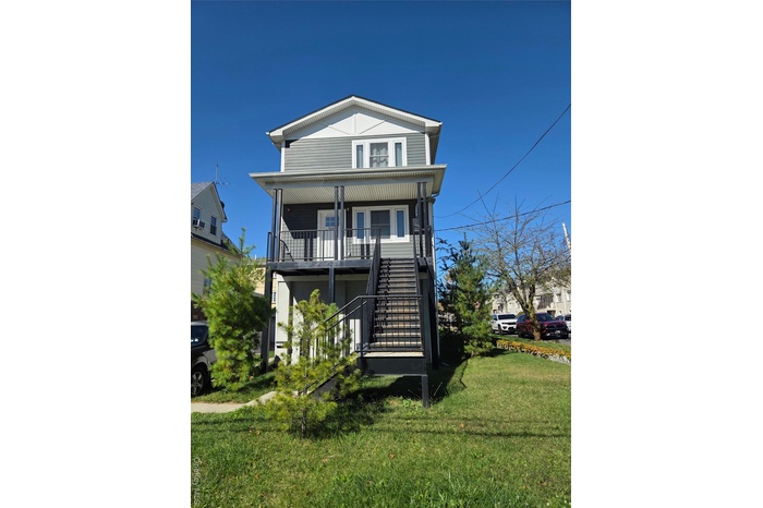 View of front of home featuring a front yard, stairway, and covered porch