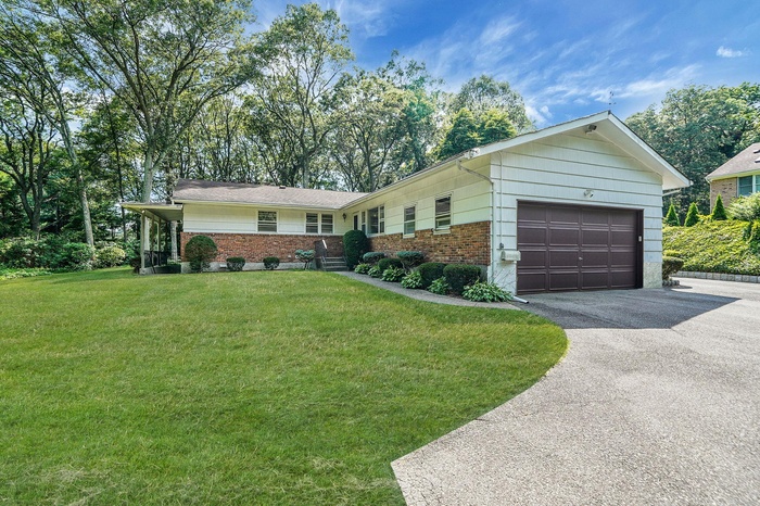 Single story home featuring brick siding, driveway, a garage, and a front yard