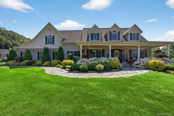 View of front of house featuring a front lawn, a porch, and a shingled roof