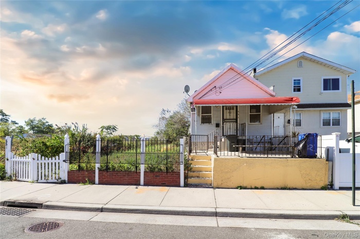 View of front of property with a porch, a fenced front yard, and a gate