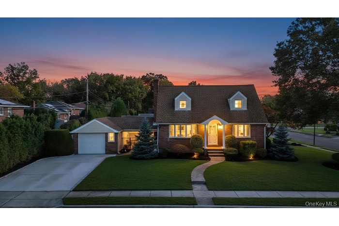 Cape cod-style house featuring concrete driveway, brick siding, a front lawn, and a chimney