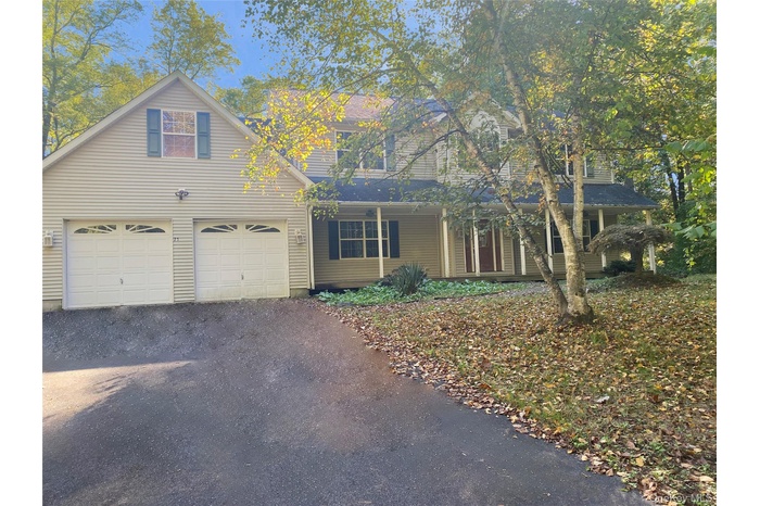 Traditional-style home with driveway, an attached garage, and a porch