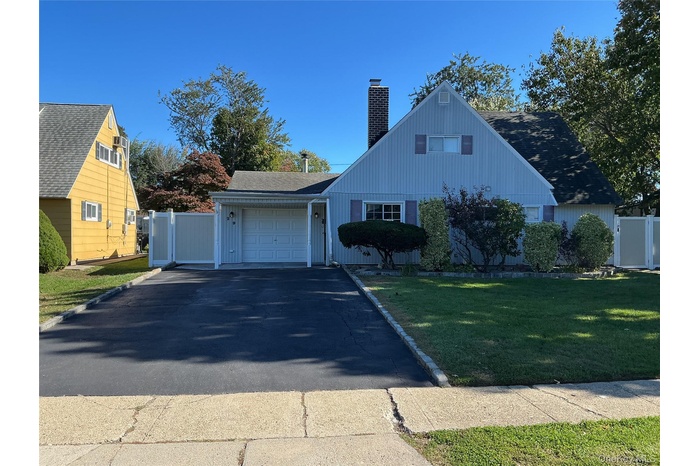 View of front of home with asphalt driveway, a garage, a chimney, and roof with shingles