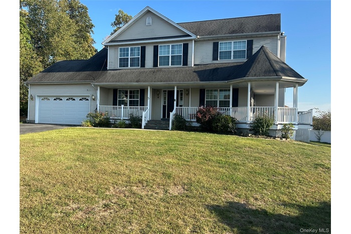 View of front of property with covered porch, a front yard, an attached garage, and driveway