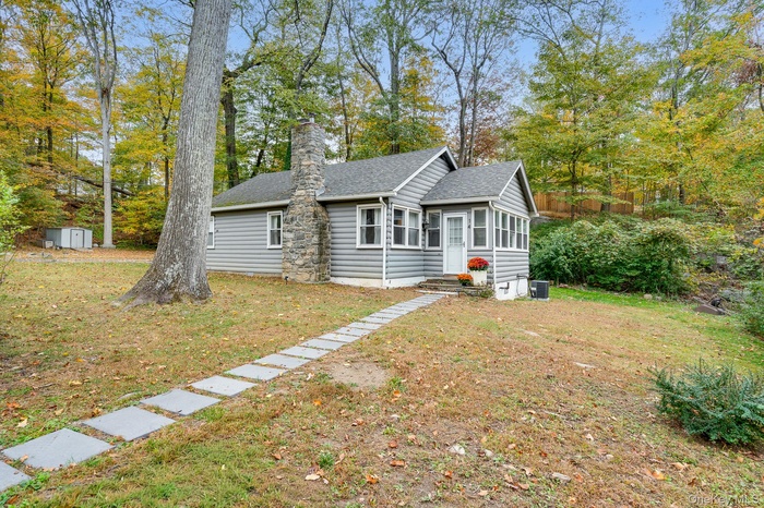 Ranch-style home featuring a front lawn, a shingled roof, a chimney, and a sunroom