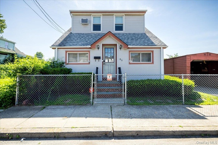 View of front of house with a gate, a fenced front yard, a shingled roof, and a wall mounted air conditioner