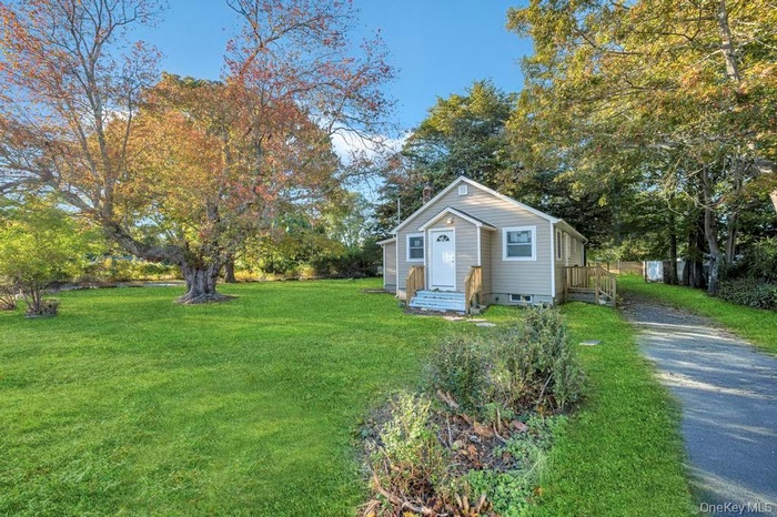 View of front of home with a front lawn and view of wooded area