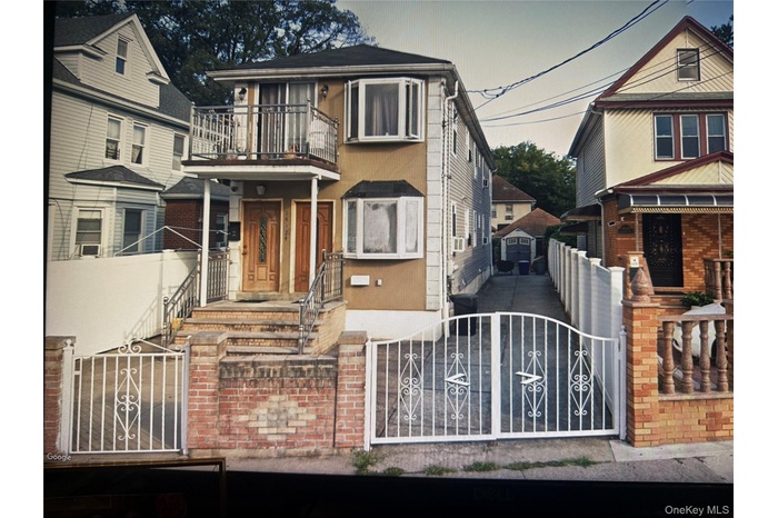 View of front of property with a gate, a fenced front yard, a balcony, an outdoor structure, and brick siding