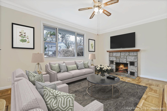 Virtually staged step down living room  with  stone fireplace, wood foors and a ceiling fan