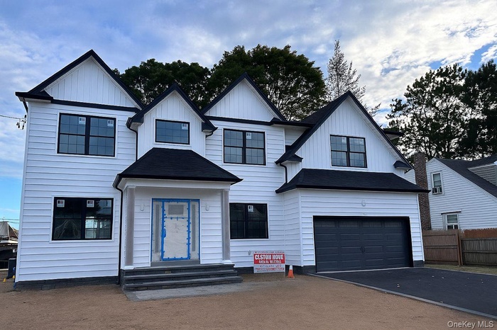Modern farmhouse with asphalt driveway, board and batten siding, an attached garage, and roof with shingles