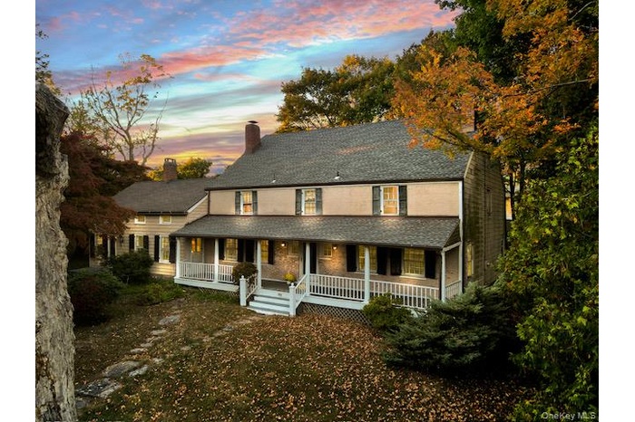 View of front of house with covered porch, a chimney, and roof with shingles